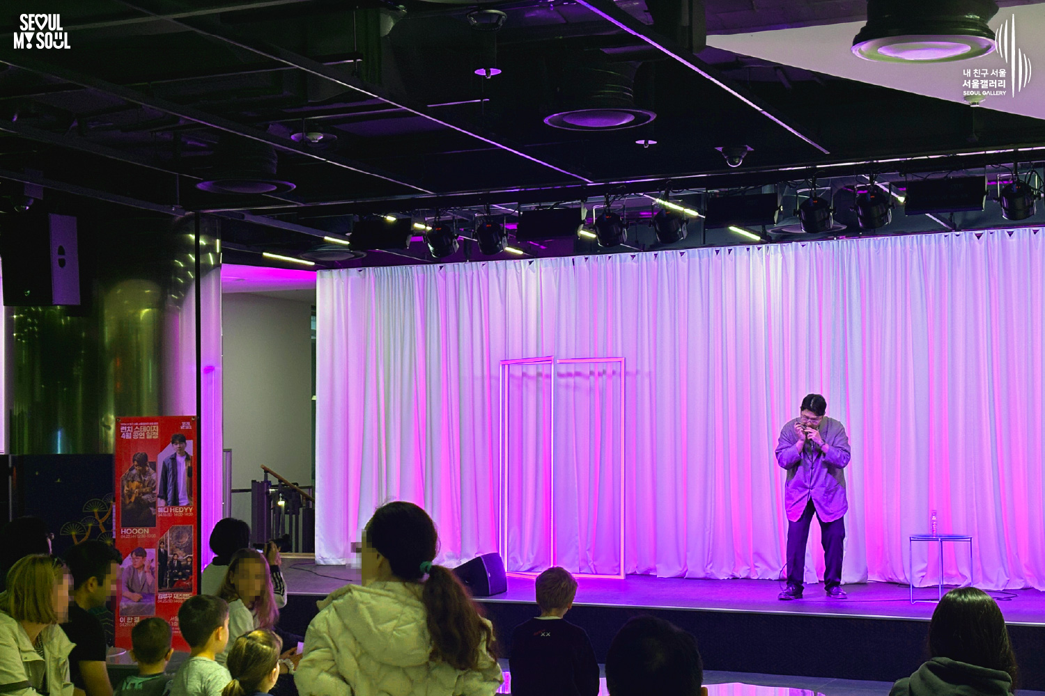 Harmonicist Lee Hangyeol plays the harmonica on a purple-lit stage during Seoul Gallery's Lunch Stage event, with audience members watching and "SEOUL MY SOUL" and "Seoul Gallery" logos visible.