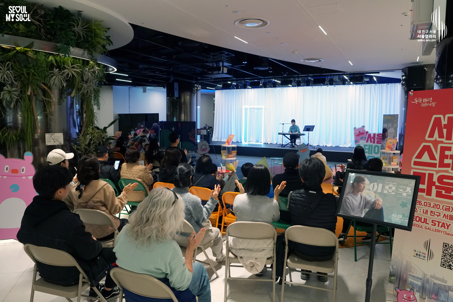 Solo musician Lee Hojun performs vocals and keyboard at Seoul Gallery's Seoul Stage Lounge event before a large seated audience, with "SEOUL MY SOUL" and "Seoul Gallery" logos visible.