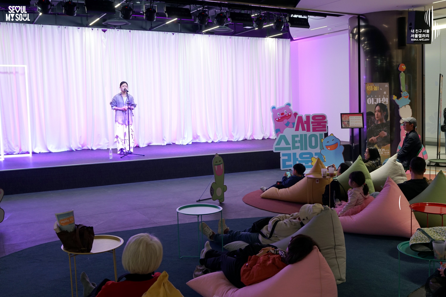 Vocalist Lee Gahyeon performs at Seoul Gallery's Seoul Stage Lounge event while audience members relax on beanbag chairs, with "SEOUL MY SOUL" and "Seoul Gallery" logos visible.