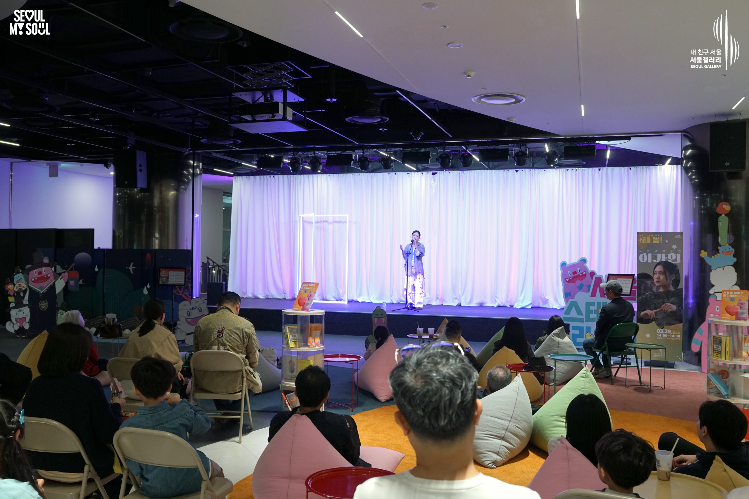 Vocalist Lee Gahyeon performs at Seoul Gallery's Seoul Stage Lounge event before a large audience relaxing on beanbags and chairs, with "SEOUL MY SOUL" and "Seoul Gallery" logos visible.