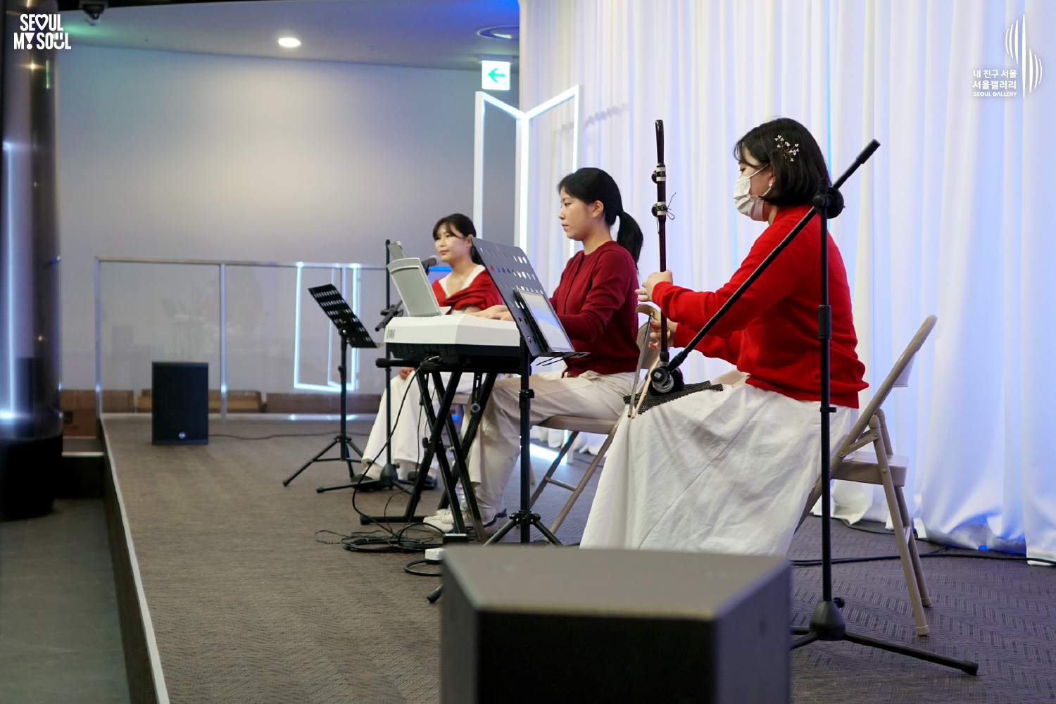 A female trio of vocal, keyboard, and haegeum performs on a white-curtained stage at Seoul Gallery, with "SEOUL MY SOUL" and "Seoul Gallery" logos visible.